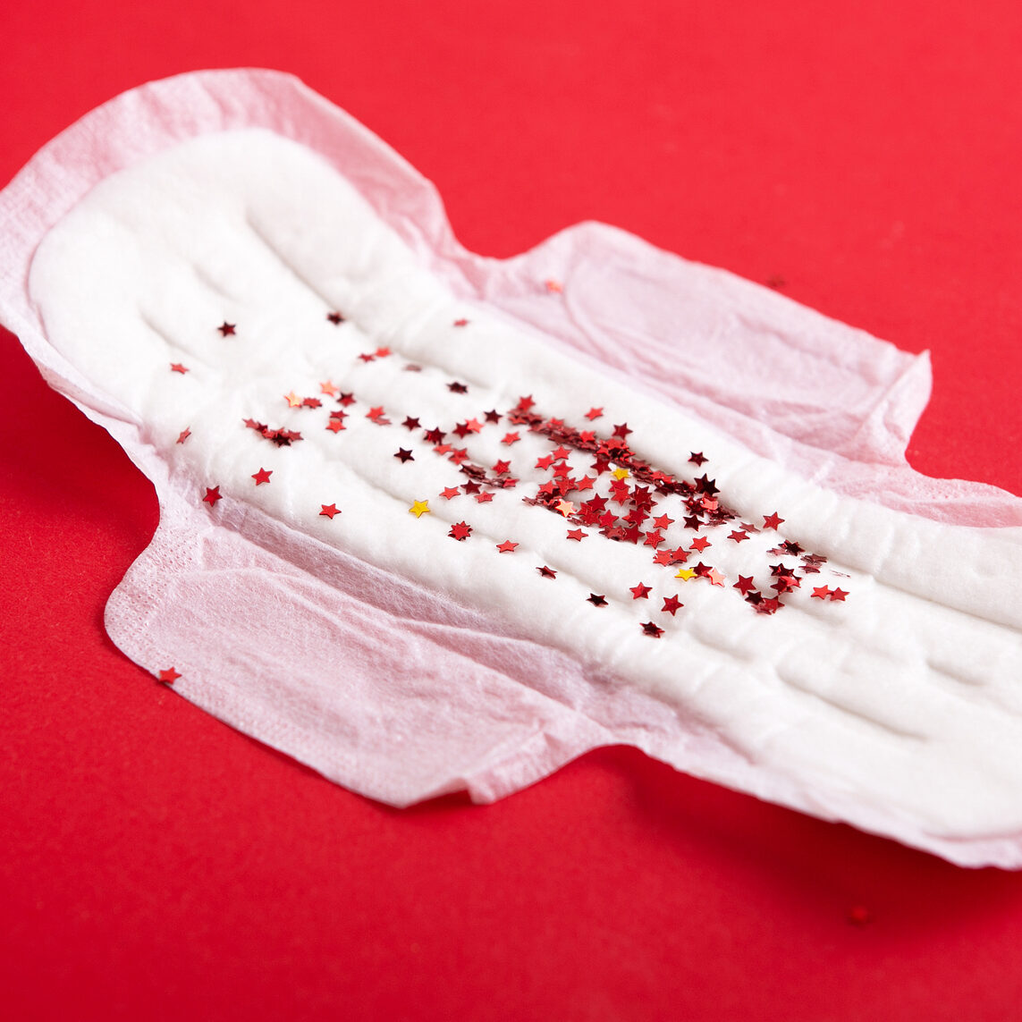 Menstruation pad with red as blood drops all over the red background, women critical days, gynecological menstruation cycle.