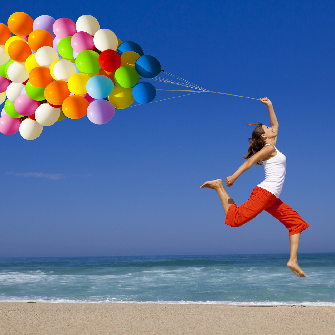 Beautiful and athletic Girl jumping with a balloon on the beach